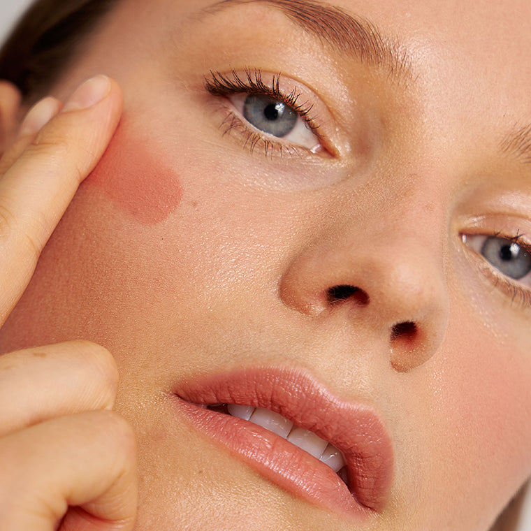 Ein Model trägt den Blush Balm in der Farbe Spring Day von PURE U. mit den Fingern auf die Wangen auf